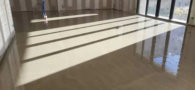 Chape liquide anhydrite autonivelante coulée dans une grande pièce, teinte beige clair caractéristique